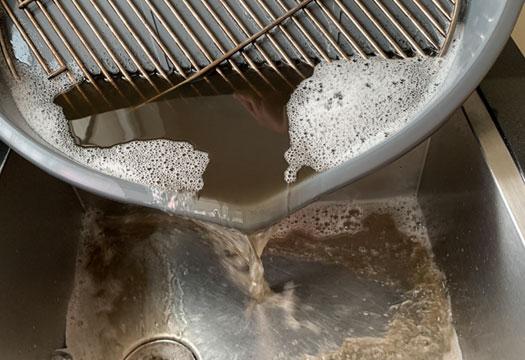 Vuil water wat vanuit de Grill Wash in de gootsteen wordt gegoten